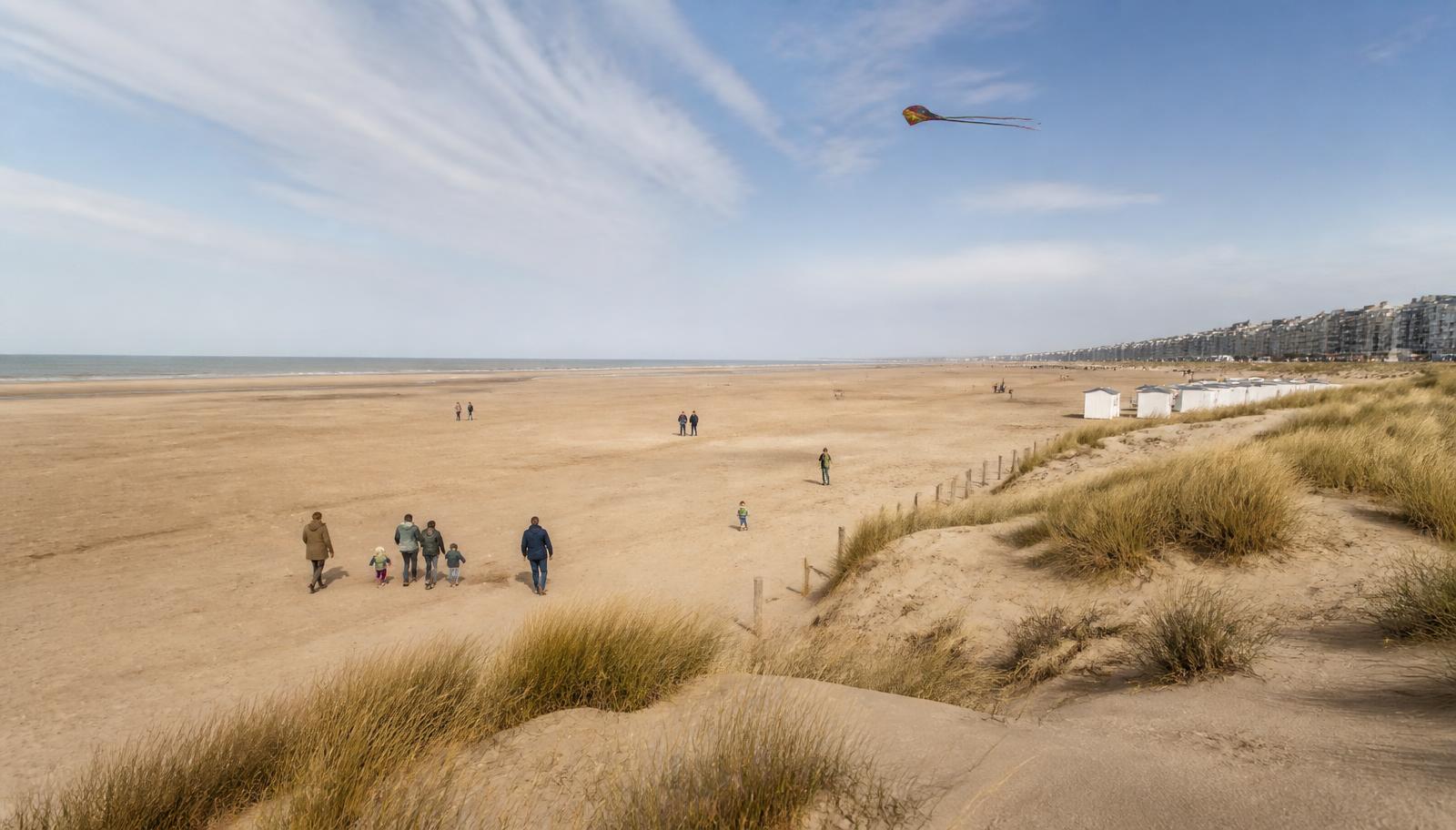 Breed zandstrand met duinen, strandcabines en wandelende gezinnen aan de Belgische kust bij De Panne.