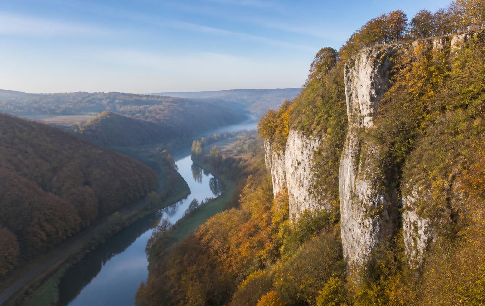 De Ourthe kronkelt door de Ardennen langs kalkstenen rotswanden en herfstbos bij Durbuy.